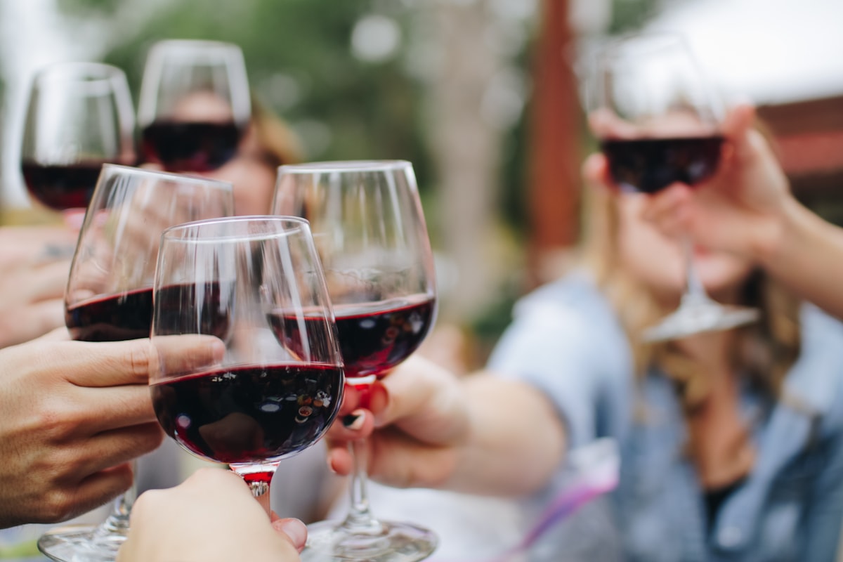 Dégustation conviviale : plusieurs verres de vin rouge levés pour trinquer